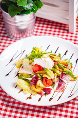 Salad with green beans, tomatoes, bell pepper, ricotta cheese and mixed greens on white plate. Close up
