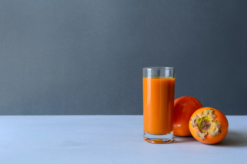 Persimmon juice with persimmons on gray wooden background. Healthy eating concept. Copy space.