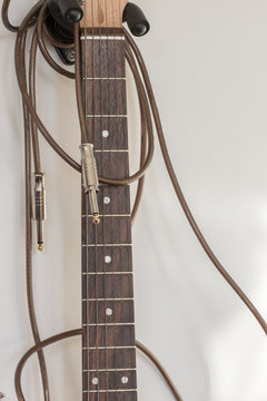 Untidy tangled guitar cable wrapped around electric guitar neck