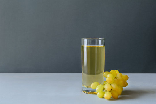 White grape juice with grapes on gray wooden background. Healthy eating concept. Copy space.