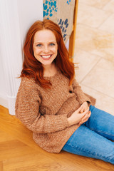 Happy, smiling, redhead woman on floor at home