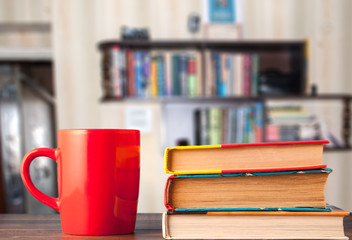 books and red cup, blurred bookshelf background
