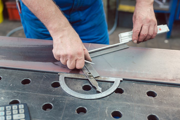 Metalworker using folding rule to measure steel strip for later cutting