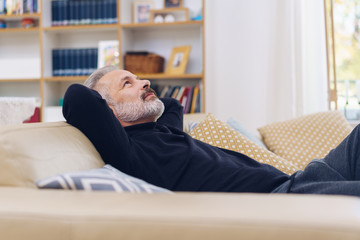 Attractive bearded man unwinding on a sofa at home