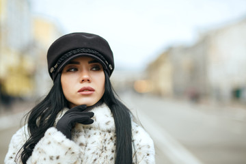 Outdoor portrait of stunning woman wearing stylish black cap and warm coat. Empty space