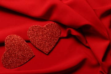 Blurred background Two red hearts on a red drape fabric. Cropped shot, horizontal, place for text, background. Valentine's day concept