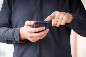 Man using mobile smartphone - focus on top of the phone