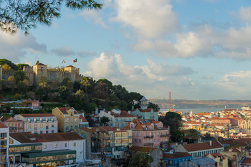 Fototapeta premium Lizbona, Portugalia - 21 listopada 2018: Zamek św. Jerzego i okolice Castelo i Mouraria. w tle most 25 kwietnia na rzece Tag