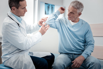 Obraz premium Attentive physician examining sick arm