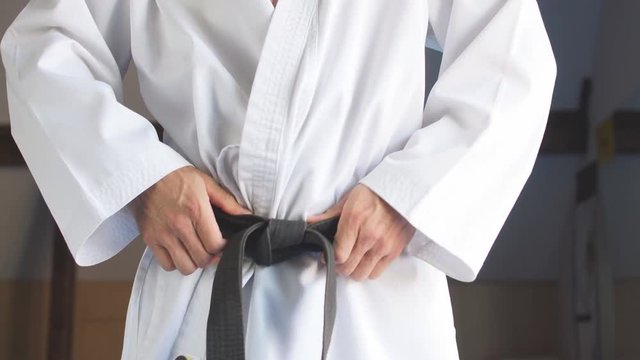karate man Hands tightening black belt on man dressed in kimono