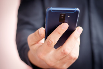 Male hand holding a cell smartphone and writing sms