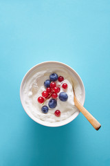 Naklejka na ściany i meble Breakfast bowl with yoghurt and berries on a blue background viewed from above. Top view. Copy space.