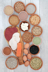 Fototapeta na wymiar High protein food selection with meat, fish, vegan tofu, legumes, dairy, supplement powders, grains and seeds. High in dietary fibre, antioxidants and vitamins. Top view on rustic wood background.