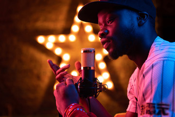 Studio portrait of young man with beard and mustaches in baseball cap and t-shirt with microphone....