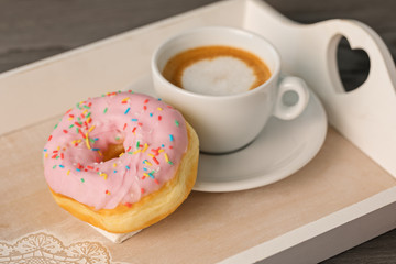 Coffee and doughnut on a tray.