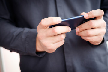 Obraz na płótnie Canvas Male hand holding a cell phone and writing sms