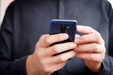 Male hand holding a cell phone and writing sms
