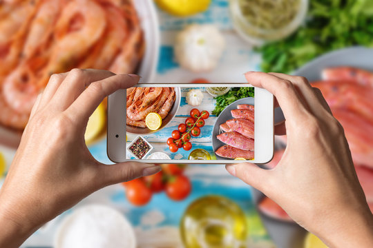 Woman Hands Taking A Photo Of Fresh Shrimps And Red Mullet Fish On Blue Wooden Background.