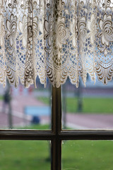 Image of vintage window with lace curtain and blurry background