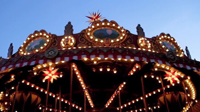 A glowing decoration of rotating carousel on a dark blue sky of sunset,Traditional Christmas Dresden Striezelmarkt. Old retro merry-go-round is turn s with illuminated light bulbs.