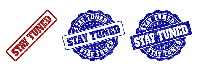 STAY TUNED scratched stamp seals in red and blue colors. Vector STAY TUNED marks with dirty texture. Graphic elements are rounded rectangles, rosettes, circles and text labels.