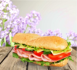Long baguette sandwich with lettuce, vegetables, ham, and cheese