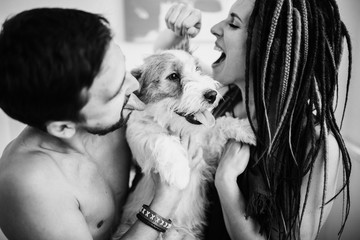 Cheerful and happy couple and the dog, smiling and showing tongue. Love story concept.