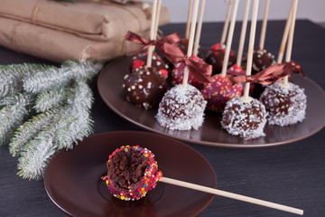 Various cake pops decorated with white and dark chocolate on a Christmas background