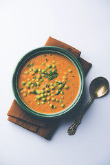 Green Peas curry / Matar masala served in a bowl over moody background. selective focus