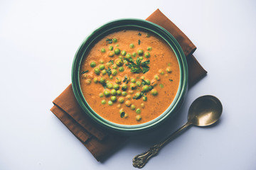 Green Peas curry / Matar masala served in a bowl over moody background. selective focus