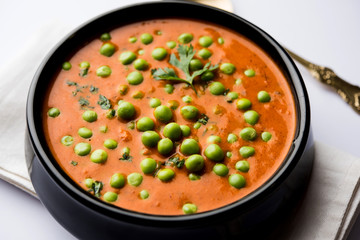 Green Peas curry / Matar masala served in a bowl over moody background. selective focus
