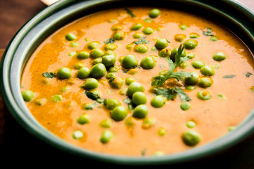 Green Peas curry / Matar masala served in a bowl over moody background. selective focus