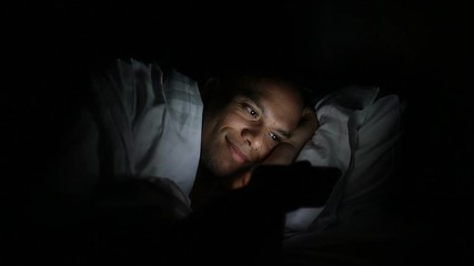 Young man in bed using his phone in the dark - Powered by Adobe