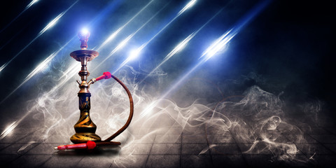 Smoking a hookah on a dark concrete field, in clouds of smoke and neon light