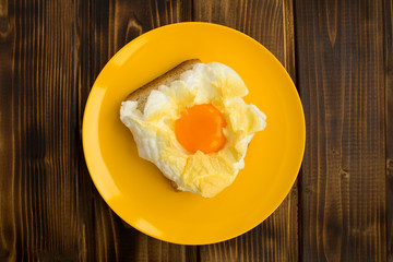 Sandwich with egg in the cloud in the yellow plate on the brown wooden  background.Top view.Copy space.