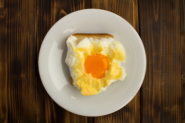 Sandwich with egg in the cloud in the white plate on the brown wooden  background.Top view.Copy space.