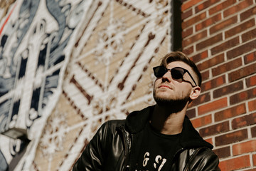 Obraz premium Portrait Headshots of a Young Handsome Attractive Modern Fashion Caucasian Male Guy Modeling near Local Outdoor Art in Urban City in Autumn Winter Season on Bright Sunny Day