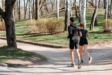 Fototapeta premium man and young woman athlete in sportswear summer early morning running in Park. healthy lifestyle concept. rear view
