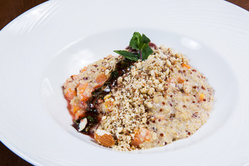 Oatmeal with nuts and sauce in white plate on dark wooden table in a restaurant. Tasty healthy food