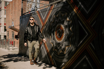 Obraz premium Portrait Headshots of a Young Handsome Attractive Modern Fashion Caucasian Male Guy Modeling near Local Outdoor Art in Urban City in Autumn Winter Season on Bright Sunny Day