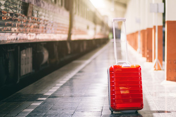 Red suitcase at railway station travel