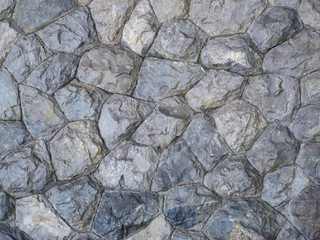 Gray wall made of natural stones of different shapes.