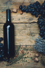Bottle of red wine (bio wine) with grapes, herbs and nuts on a wooden background background of an old wooden table. Copy space.