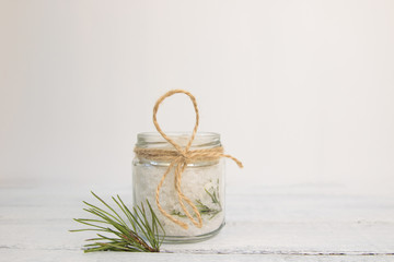 Fototapeta na wymiar Natural herbal sea salt with aromatic fir - perfect for relaxation. Cosmetic jars and bottles with salt, lavender flowers