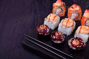 Sushi rolls assortment on a black board