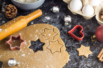 Cooking Christmas gingerbread cookies with ingredients and decor on a dark background