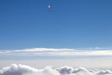 Foto op Plexiglas Luchtsport Blue sky with sunlight clouds and silhouette of paraglider