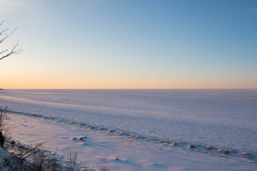 Fototapeta na wymiar Snowy and frozen open seascape in cold winter weather during sunset.