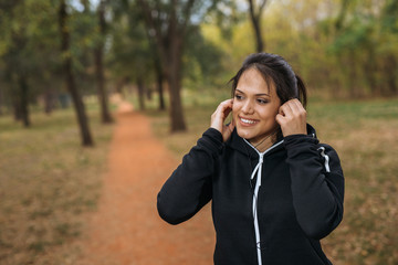 Portrait of young sports woman preparing for training in park
