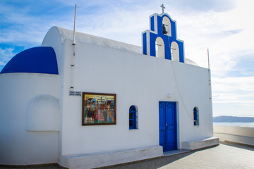 Santorini Island, Greece - November 17, 2016: blue domes and white walls of the church on the famous romantic island of Santorini on the background of the Aegean Sea on a clear sunny day